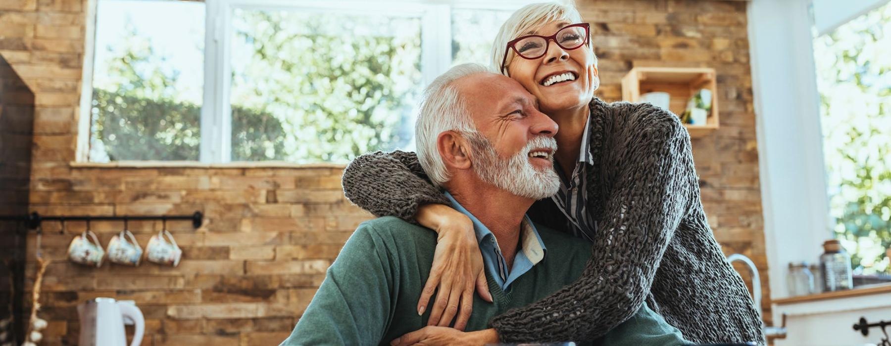 older couple hugging in their sun-filled kitchen